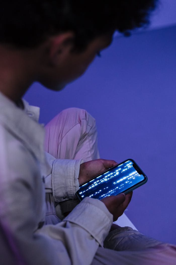 gallery-04 Teenager casually browsing on smartphone indoors, focused on screen.